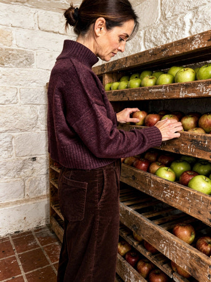 Burgundy jumper in claret worn with corduroy trousers, side view