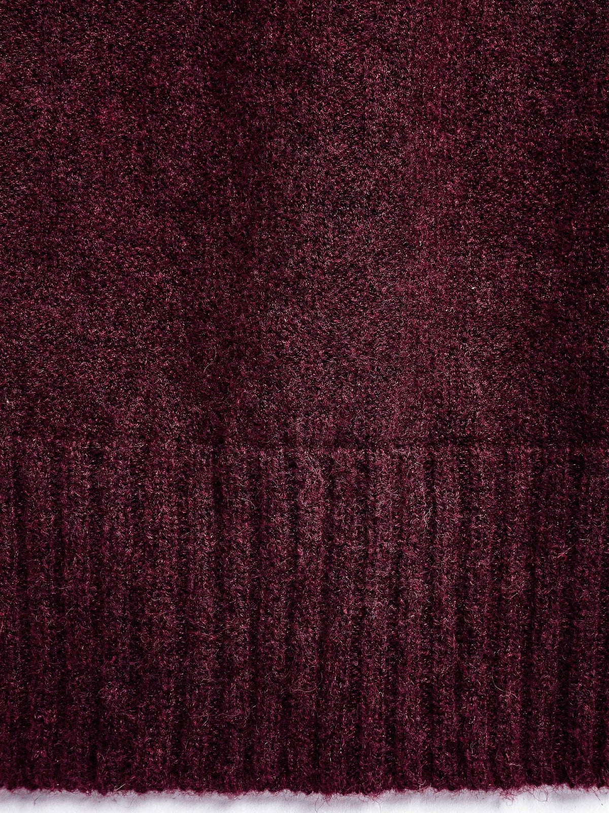 Close-up of the brushed marl knit and the deep ribbed hem of the burgundy jumper