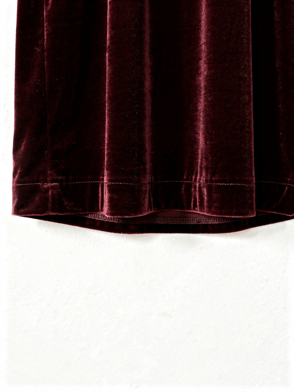 Close view of the velvet pile and the plain continuous hem of the burgundy velvet dress