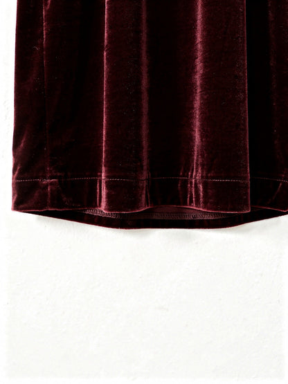 Close view of the velvet pile and the plain continuous hem of the burgundy velvet dress