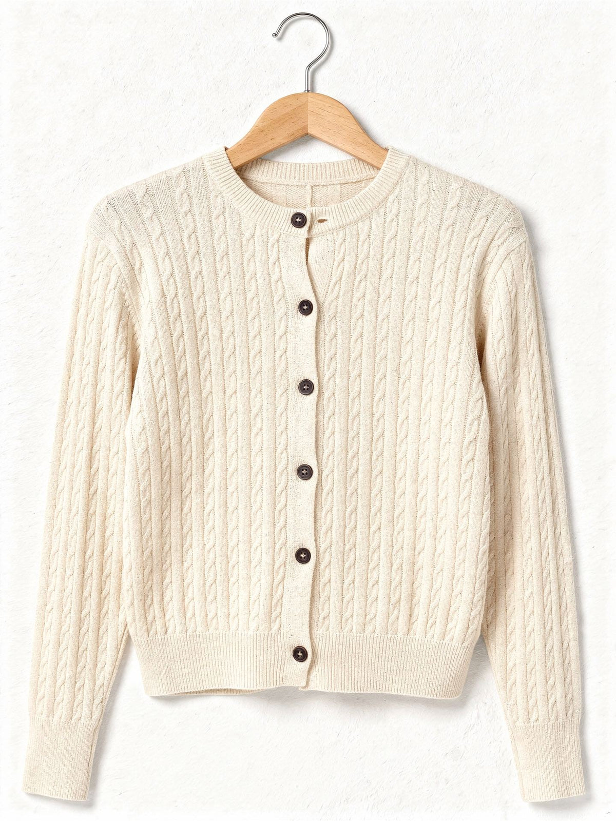 Cable knit cardigan in Creamware on a wooden hanger, front view