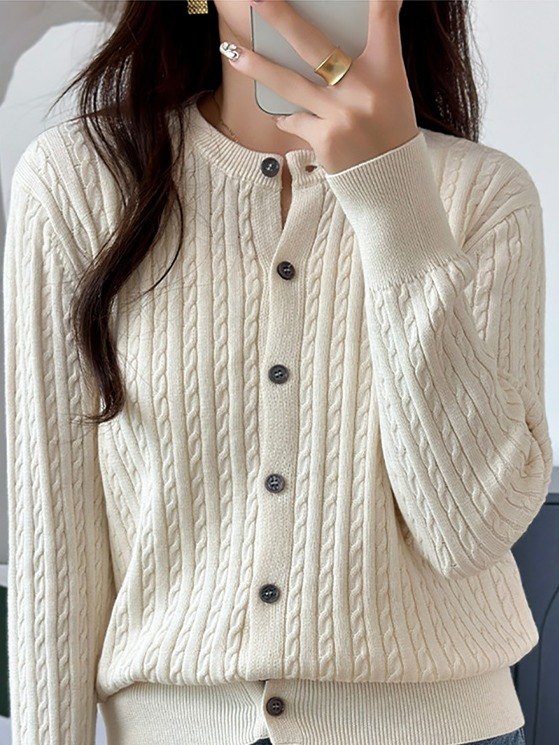 Cable knit cardigan in Creamware worn buttoned with jeans