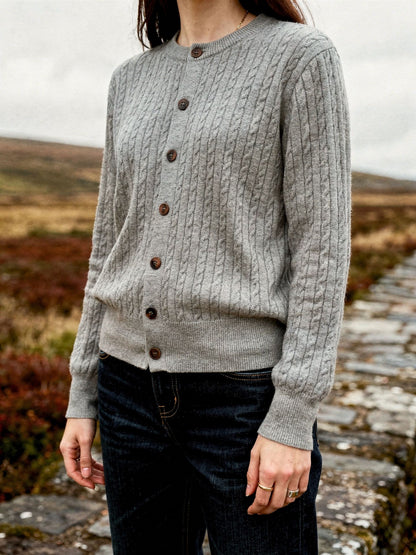 Womens cable knit cardigan in Harbour Grey, worn with dark jeans on a moorland bridge