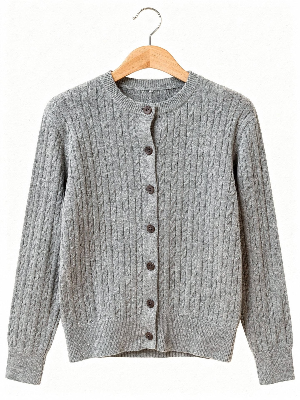 Cable knit cardigan in Harbour Grey on a wooden hanger, front view