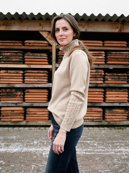 Womens cable knit roll neck jumper in Fawn worn with jeans at an English tile works