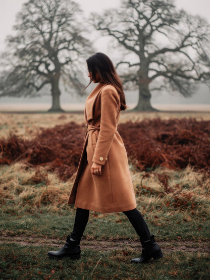 Camel belted longline wrap coat worn in profile in an English deer park in autumn