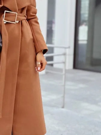 Belt and buckle of the camel belted longline wrap coat worn at the waist