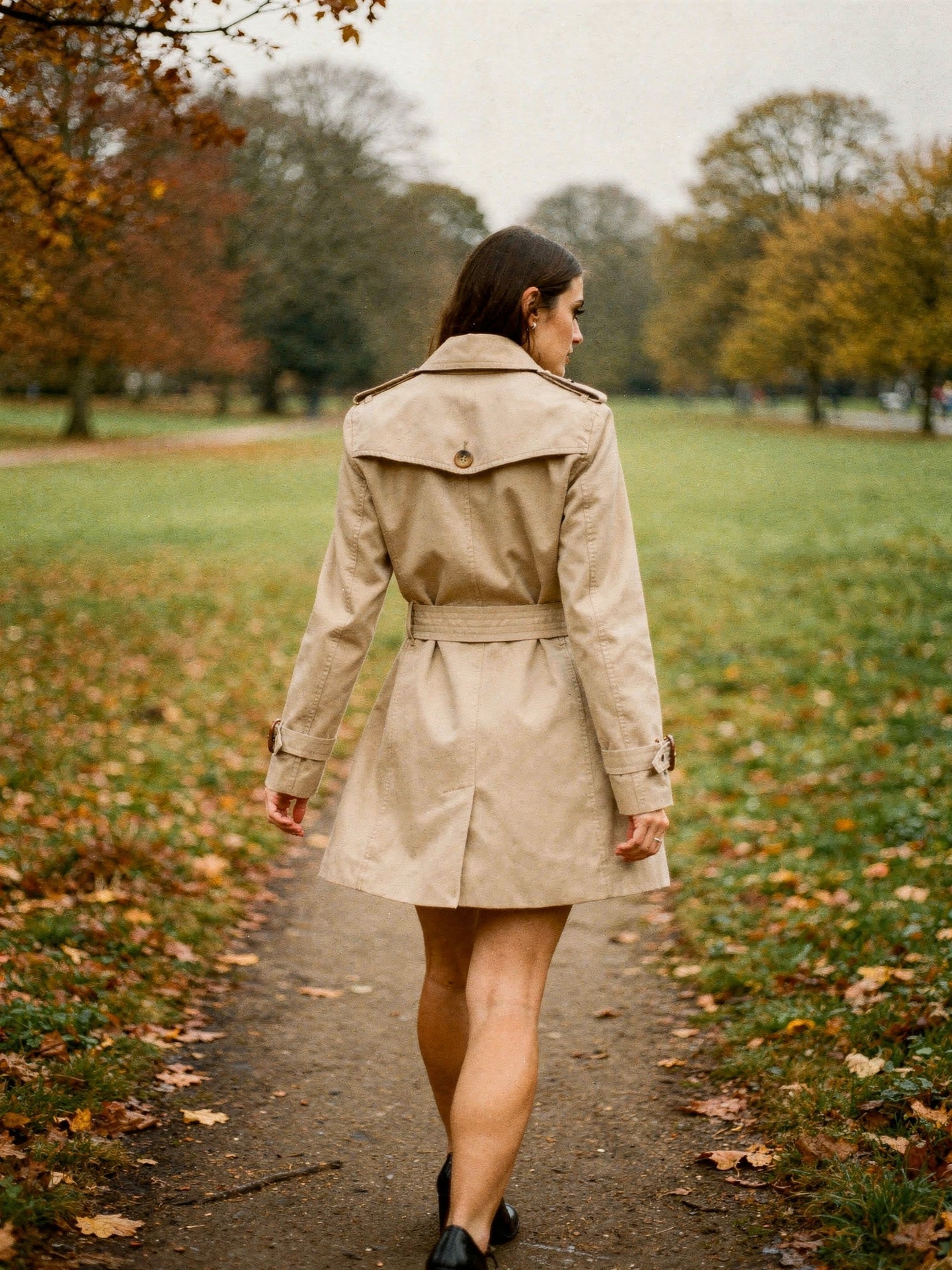 Camel belted trench coat, back view in an autumn park