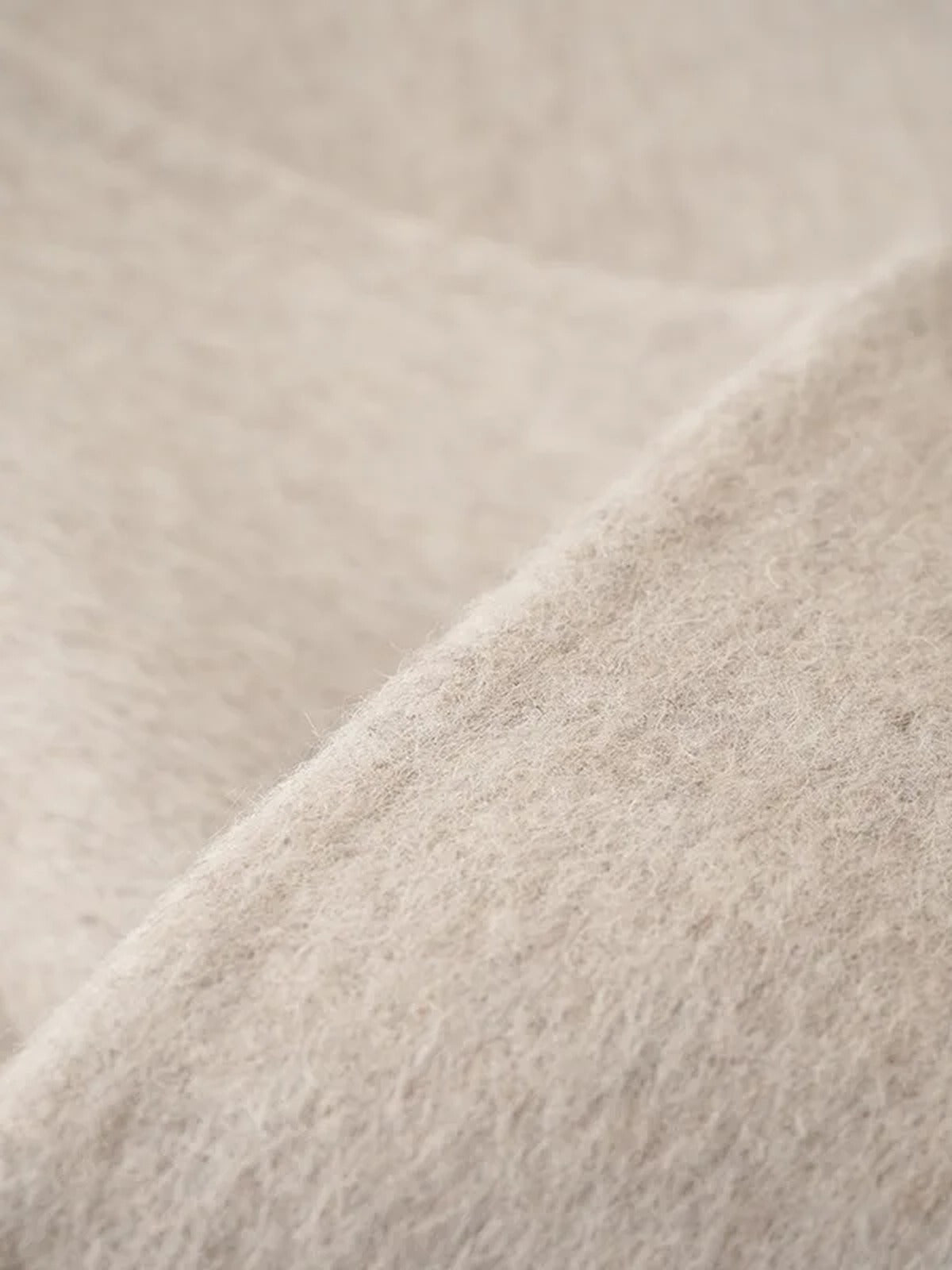 Close-up of the brushed double-faced cloth of the cape coat, showing the soft nap and the clean cut edge