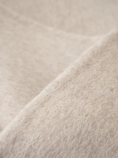 Close-up of the brushed double-faced cloth of the cape coat, showing the soft nap and the clean cut edge