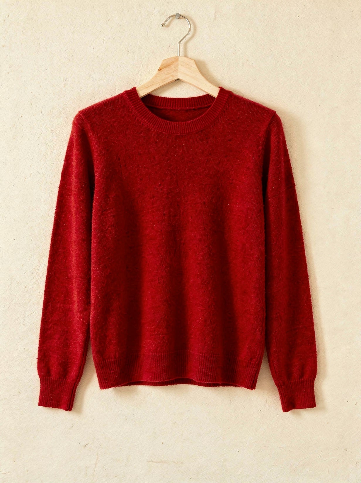 Ruby red cashmere crew-neck jumper on a wooden hanger