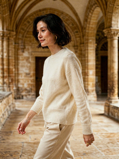 Winter white cashmere crew-neck jumper worn in a stone cathedral cloister
