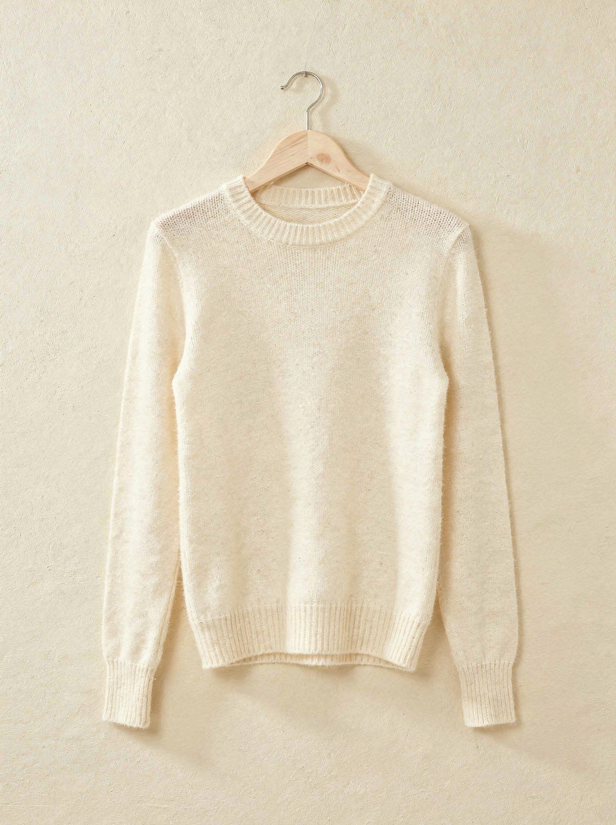 Winter white cashmere crew-neck jumper on a wooden hanger
