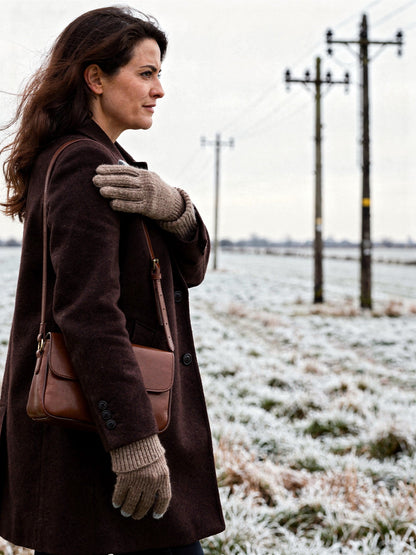 The Partridge cashmere gloves worn on a frosted winter field, seen in profile with the ribbed cuff over the coat sleeve