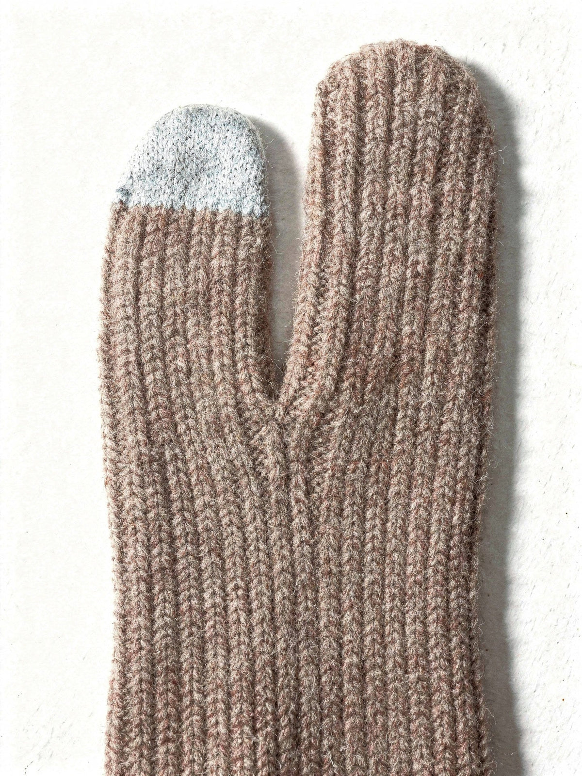 Close up of the fine rib knit of the cashmere gloves and of the grey touchscreen tip knitted into the finger