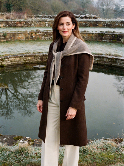 Cashmere triangle scarf in Clay worn open across the shoulders beside frosted terraced ponds