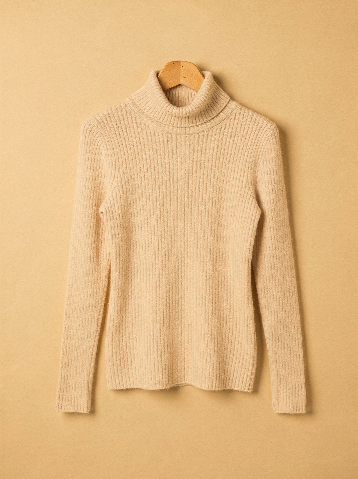 Almond cashmere turtleneck jumper on a wooden hanger