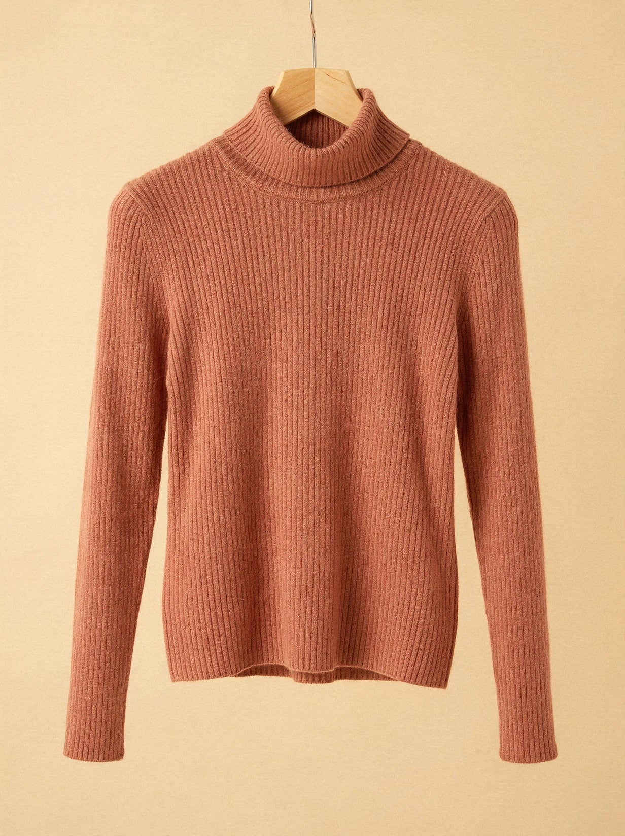 Terracotta cashmere turtleneck jumper on a wooden hanger