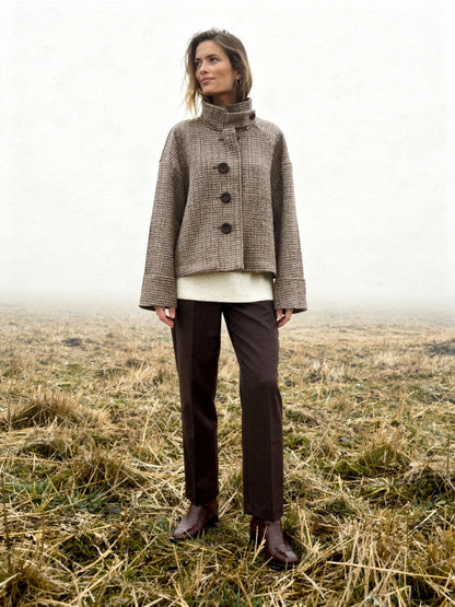 Womens check jacket in Russet houndstooth, worn buttoned in a misty winter field with the tall funnel collar standing up