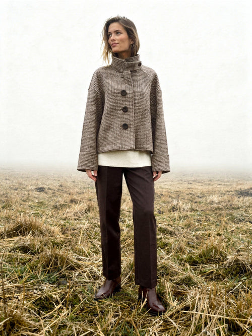Womens check jacket in Russet houndstooth, worn buttoned in a misty winter field with the tall funnel collar standing up