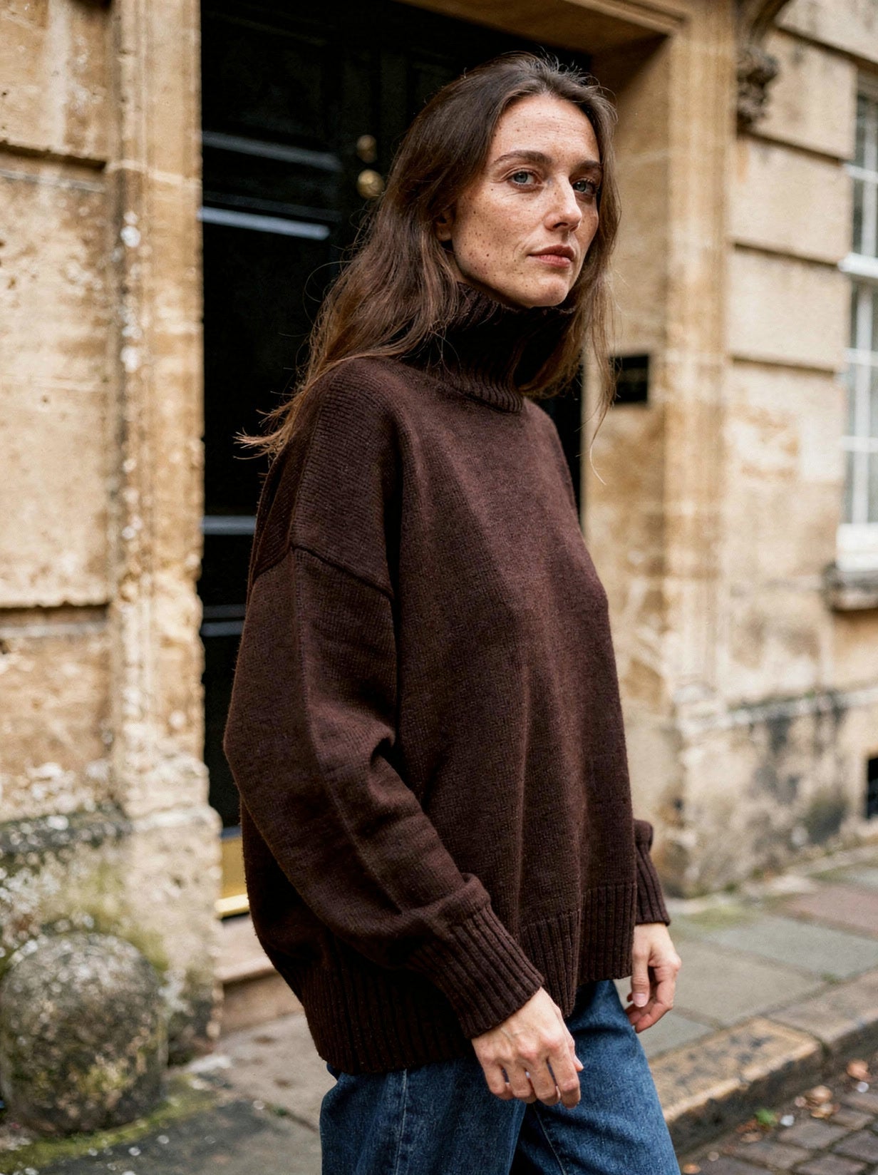 Model wearing the chocolate brown chunky knit turtleneck jumper, side view