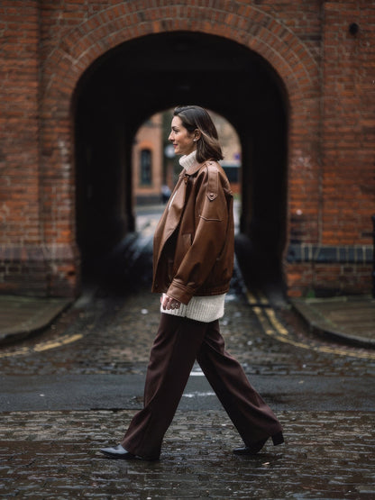 Cognac faux leather jacket worn open over a cream jumper