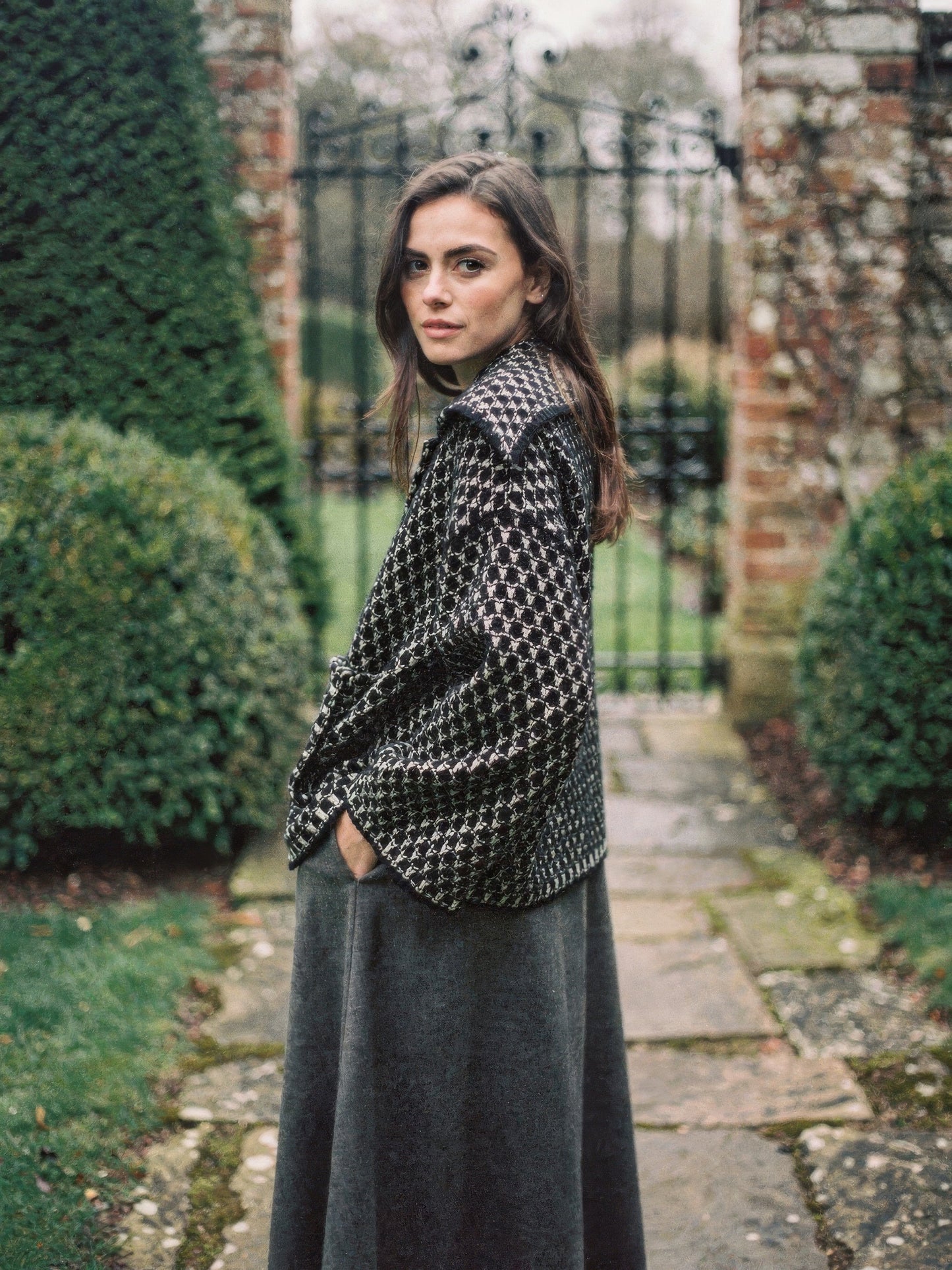 Black ecru collared cardigan in two-tone textured knit, worn in an English garden