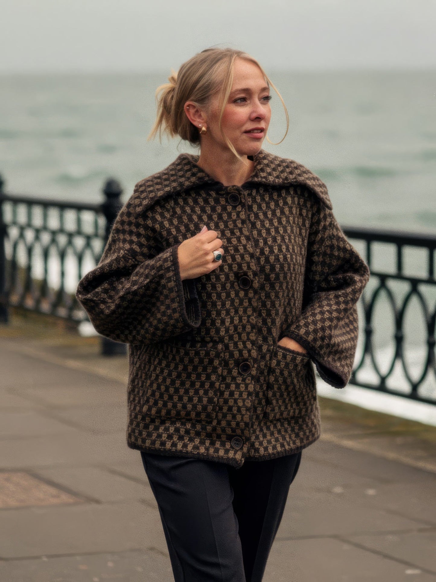 Womens collared cardigan in cocoa brown chunky two-tone knit, worn buttoned on a quiet seaside esplanade | Ledbury