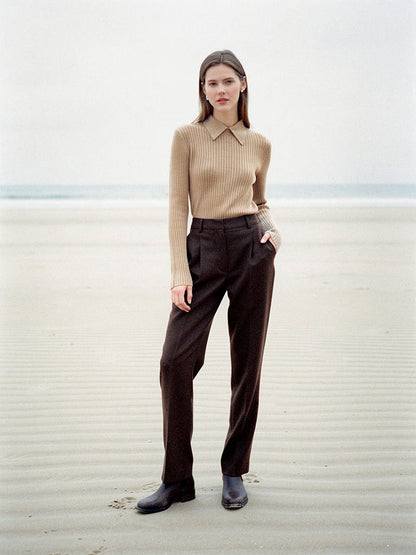 Camel collared jumper worn with dark brown wool trousers on an empty sand beach, showing the knitted point collar and the wide rib knit