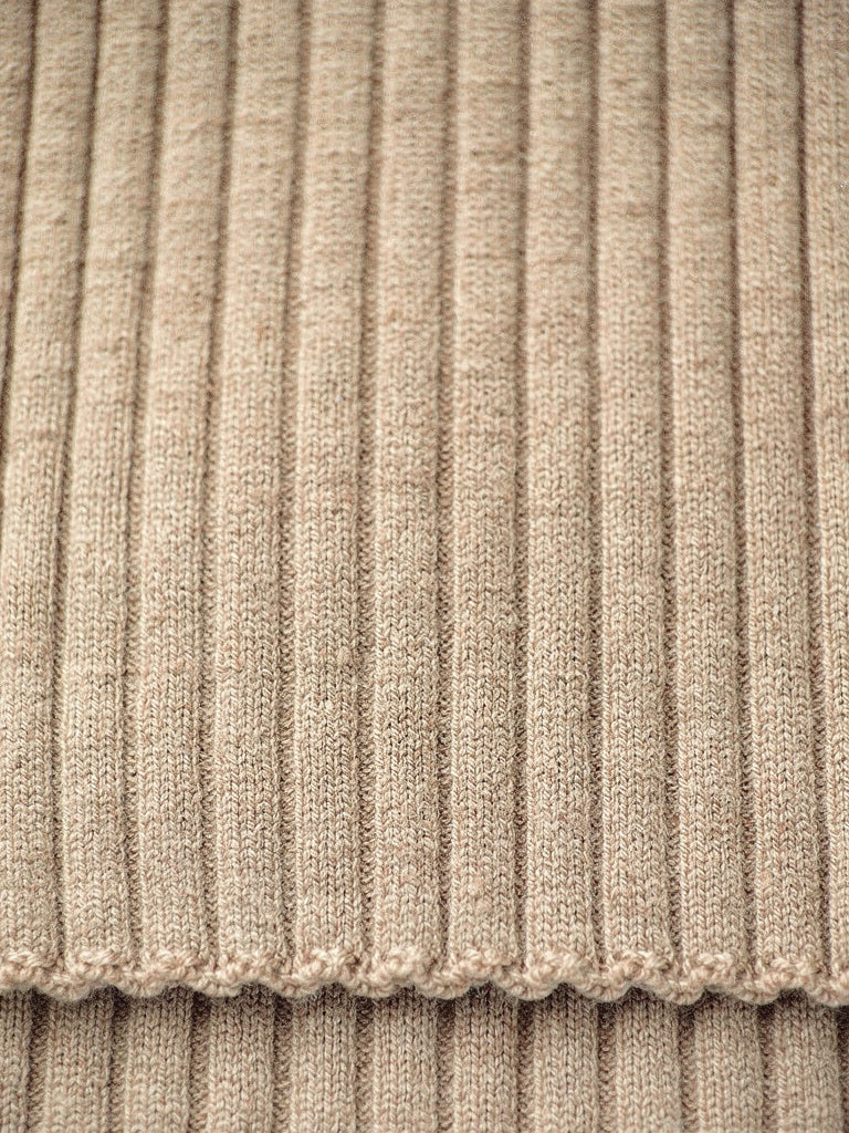 Close-up of the wide rib knit of the camel collared jumper, with the scalloped edge of the cuff
