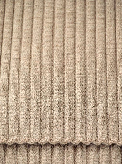 Close-up of the wide rib knit of the camel collared jumper, with the scalloped edge of the cuff
