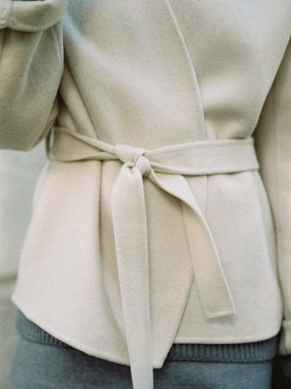 Close up of the brushed cloth and the self tie belt of the Eastleach cream wrap jacket