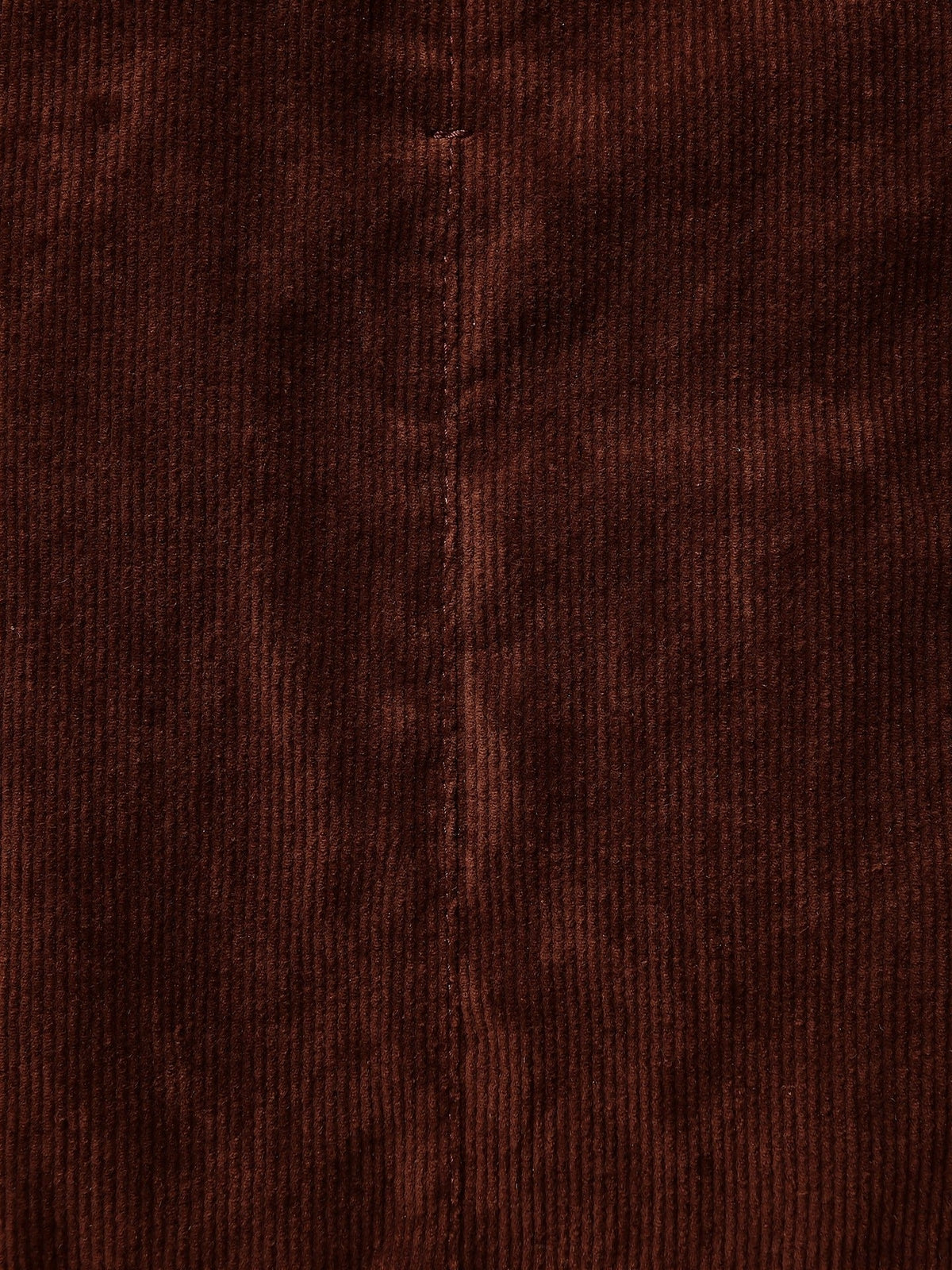 Close-up of the corduroy on the Amarone burgundy skirt, the ribs running straight down the cloth either side of a topstitched seam