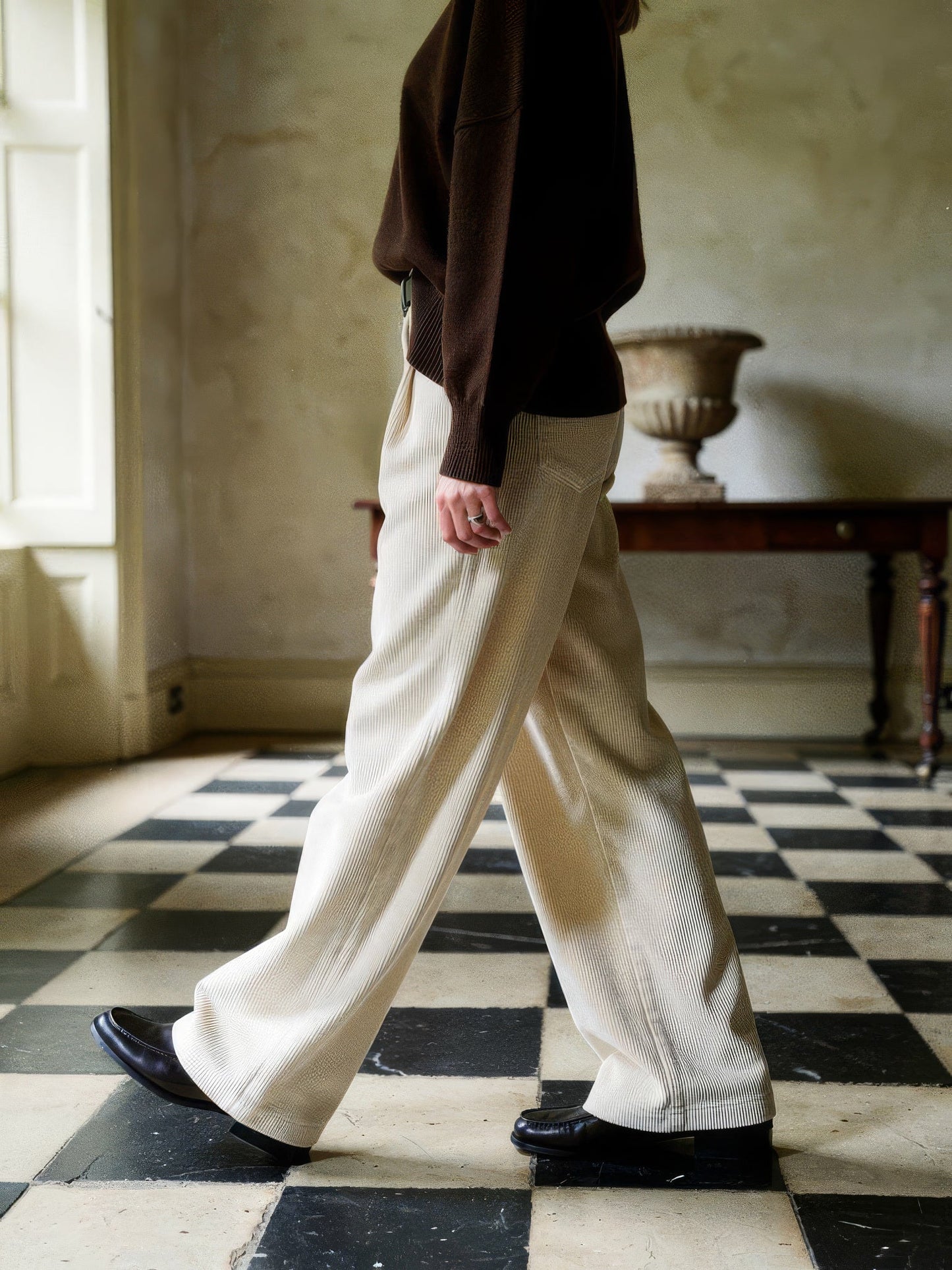 Corduroy wide-leg trousers in Parchment worn walking across a chequerboard stone floor