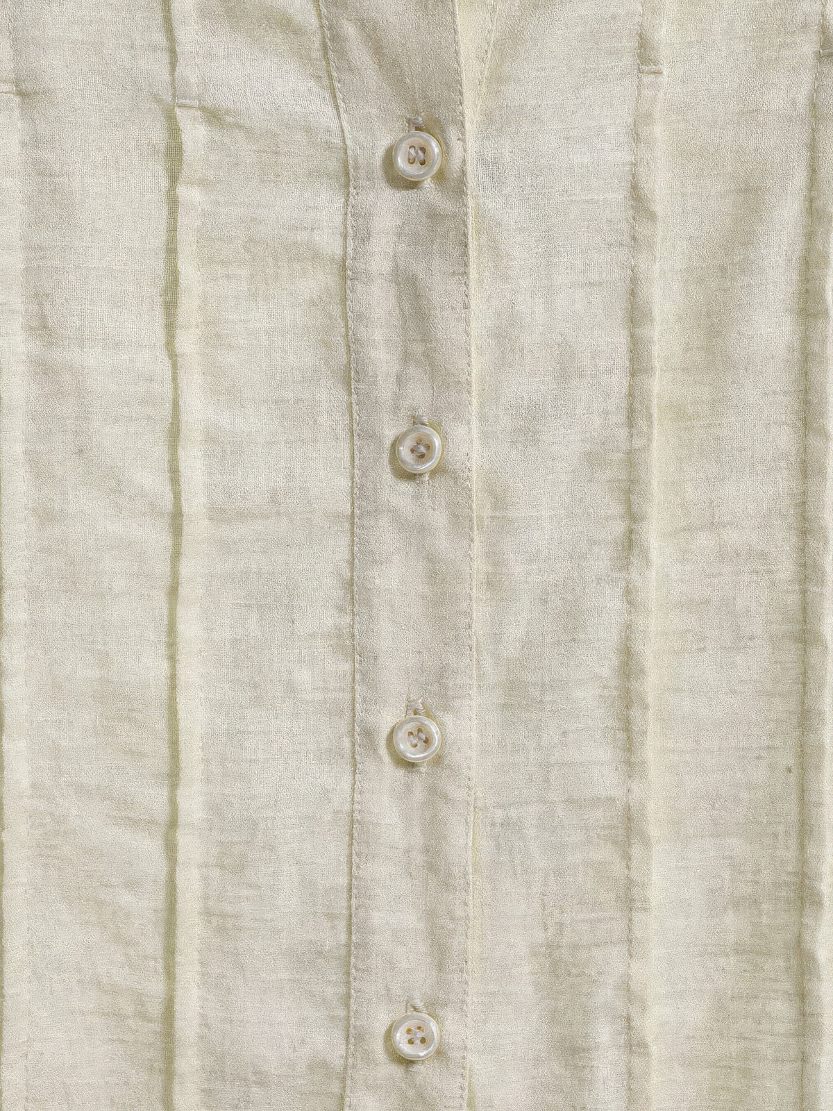 Close up of the slub weave, sewn pintucks and pearl look buttons on the cream blouse