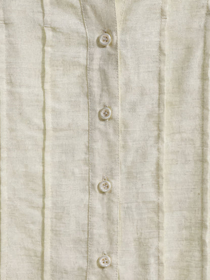 Close up of the slub weave, sewn pintucks and pearl look buttons on the cream blouse