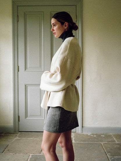 Cream collarless wrap jacket seen from the side, showing the dolman sleeve and dropped shoulder