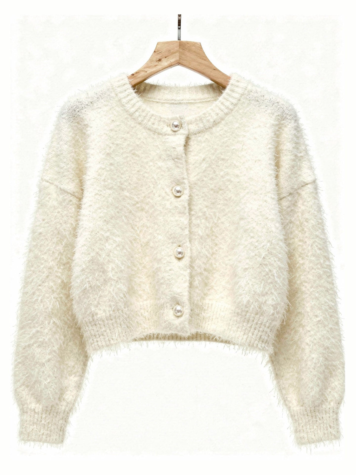 Cream fluffy cardigan on a hanger showing the four pearl buttons and ribbed hem