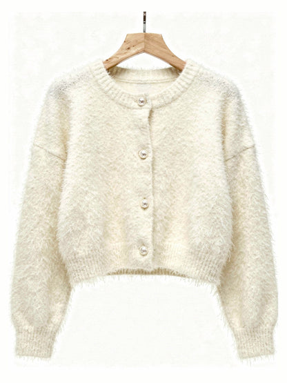 Cream fluffy cardigan on a hanger showing the four pearl buttons and ribbed hem