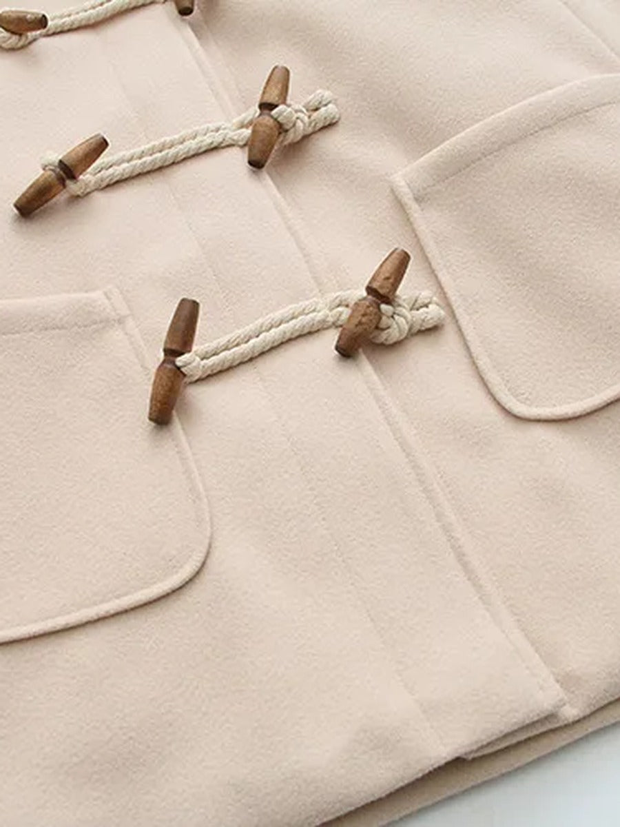 The two patch pockets and lower toggles of the cream hooded coat