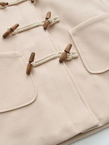 The two patch pockets and lower toggles of the cream hooded coat