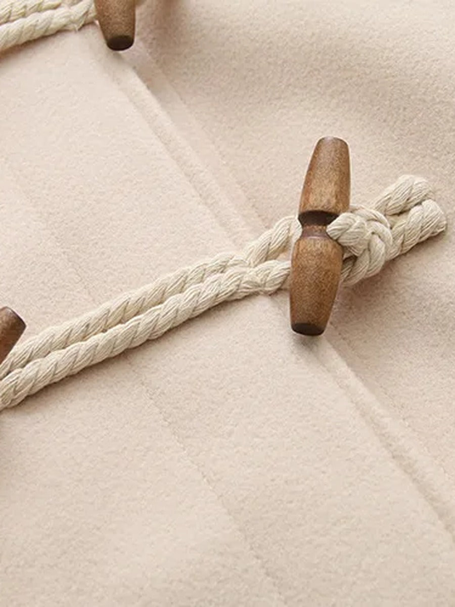 Close view of a wooden barrel toggle on a braided cream rope loop against brushed cream cloth