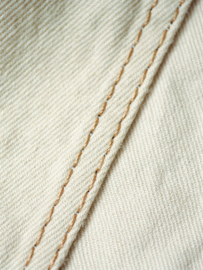 Close-up of the pale cream cotton denim twill and camel contrast topstitching of the cream jeans