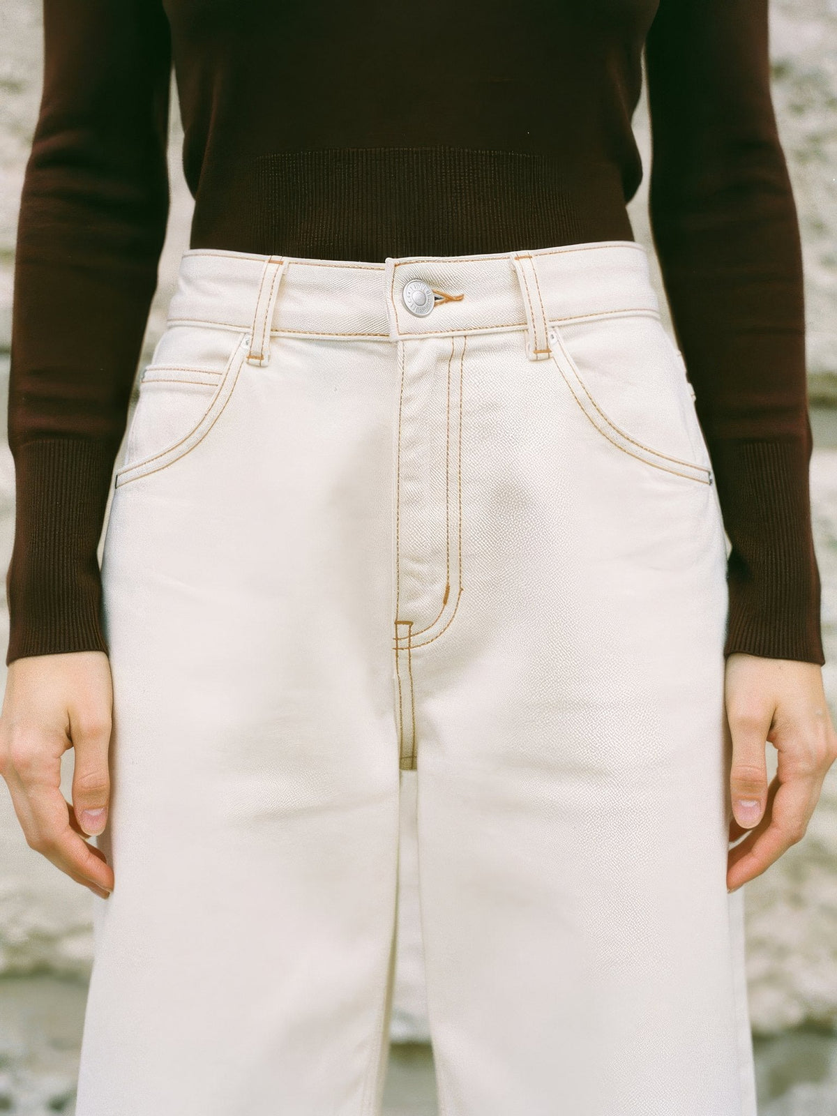 High waistband of the cream jeans with belt loops, one button, zip fly and curved front pockets