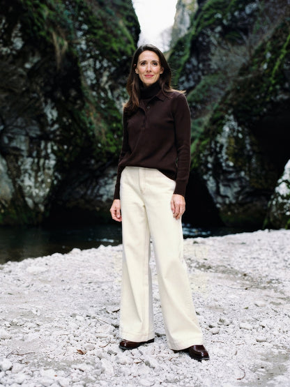 Cream jeans worn with a brown polo neck at the foot of a limestone gorge, high-rise wide leg, full length