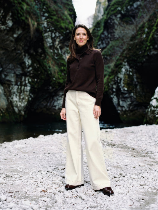 Cream jeans worn with a brown polo neck at the foot of a limestone gorge, high-rise wide leg, full length