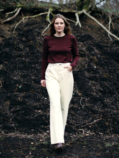 Cream jeans worn walking in a winter wood, wide leg falling full length over ankle boots