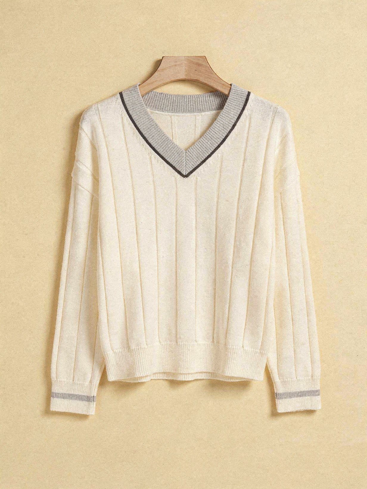 Ivory V-neck cricket jumper with pale grey contrast collar on a wooden hanger