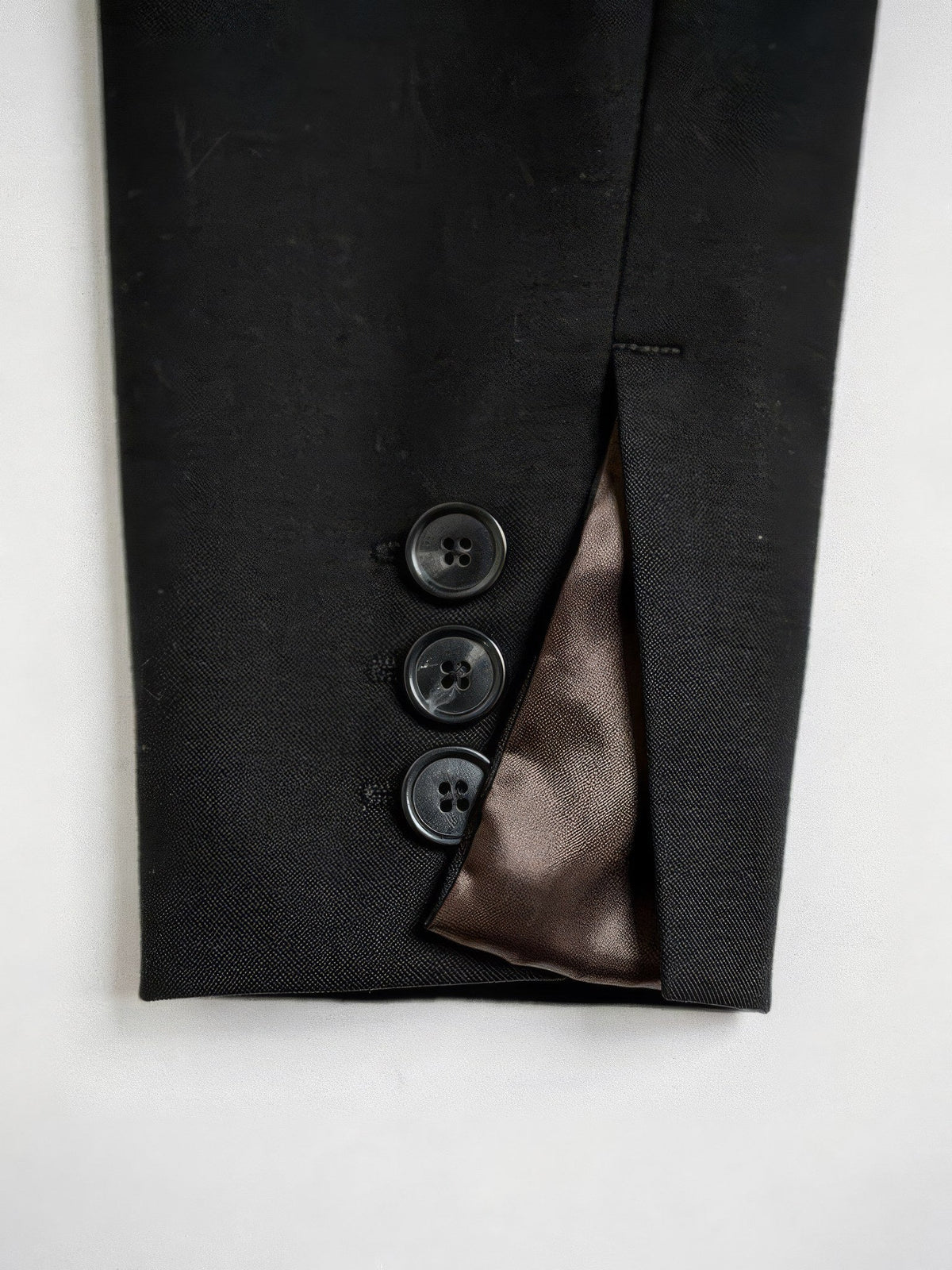 Cuff of the black cropped blazer with three buttons and satin lining