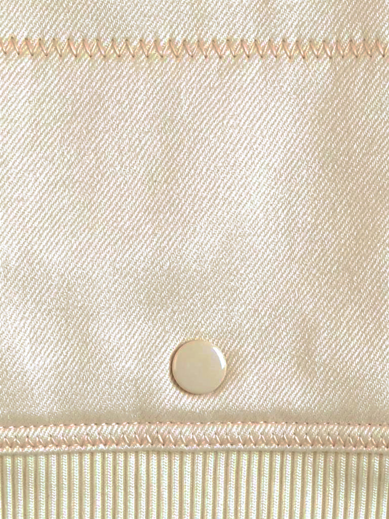 Close up of the smooth twill weave of the cropped bomber jacket, with a flat cream press stud and the ribbed hem band